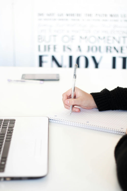 Handwriting on paper beside a laptop - representing HUADYN’s transparent creative process from thought to execution